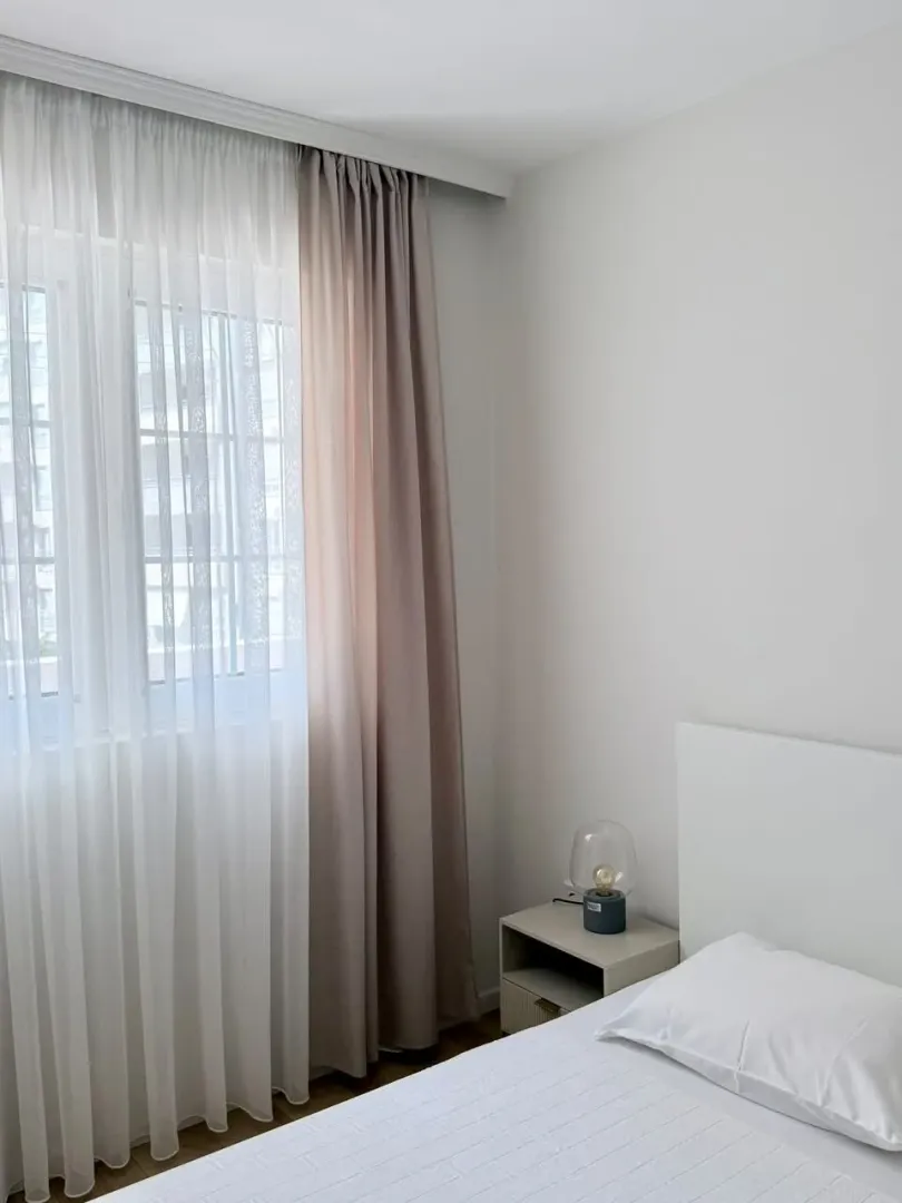 Bright bedroom with a bed and a nightstand by the window.