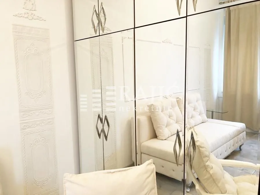 Living room with white furniture and a large mirrored wardrobe.