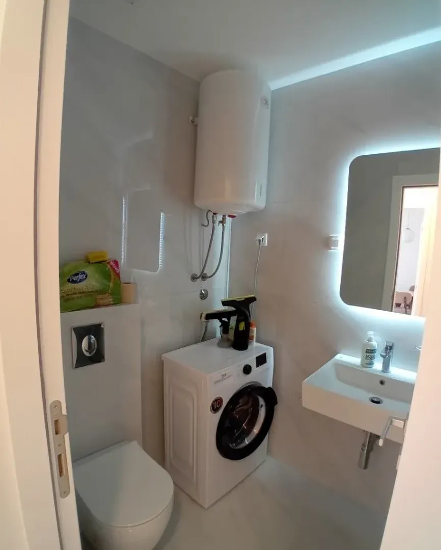 Modernly equipped bathroom with sanitary fixtures, washbasin, and washing machine.