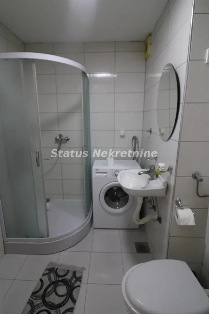 Kupatilo opremljeno tuš kabinom, umivaonikom, WC šoljom i veš mašinom.
