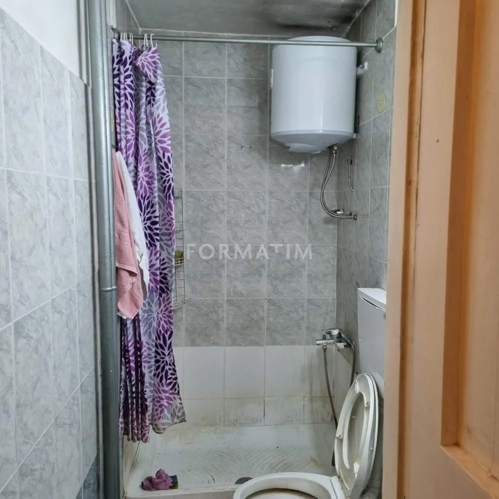 Small bathroom with a shower cabin and water heater.