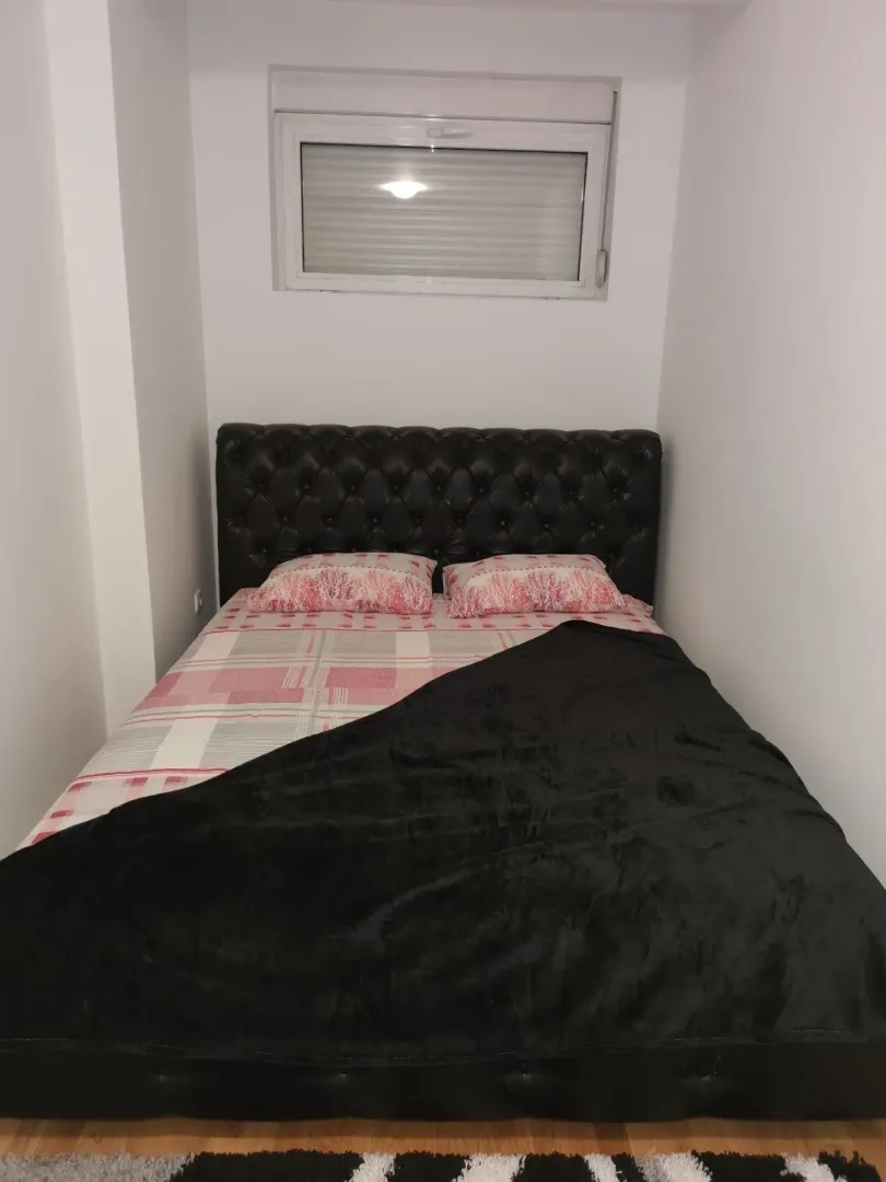Simple bedroom featuring a double bed with a leather headboard.