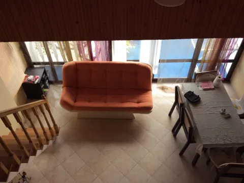 Dnevni boravak sa narandžastim kaučem, trpezarijskim stolom i drvenim stepenicama posmatran odozgo. - image 7