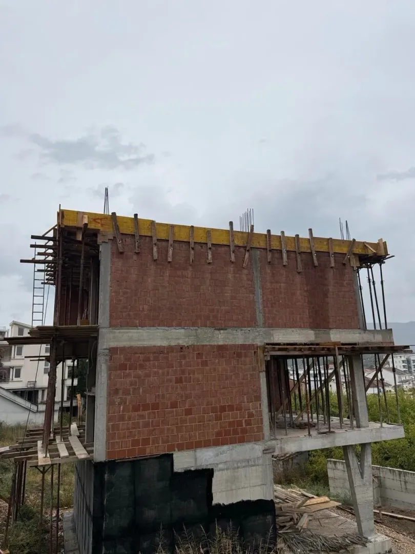 View of a residential building under construction with concrete structure and bricks.