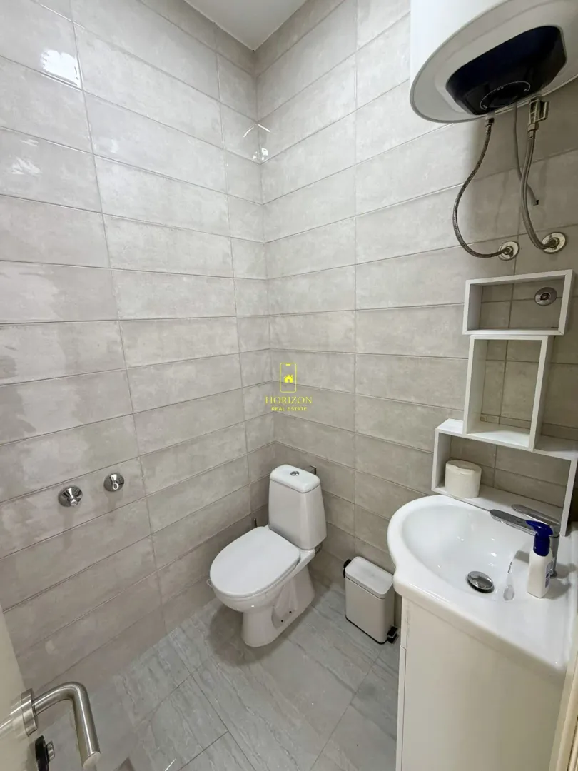 Small bathroom with light tiles, toilet, and washbasin.