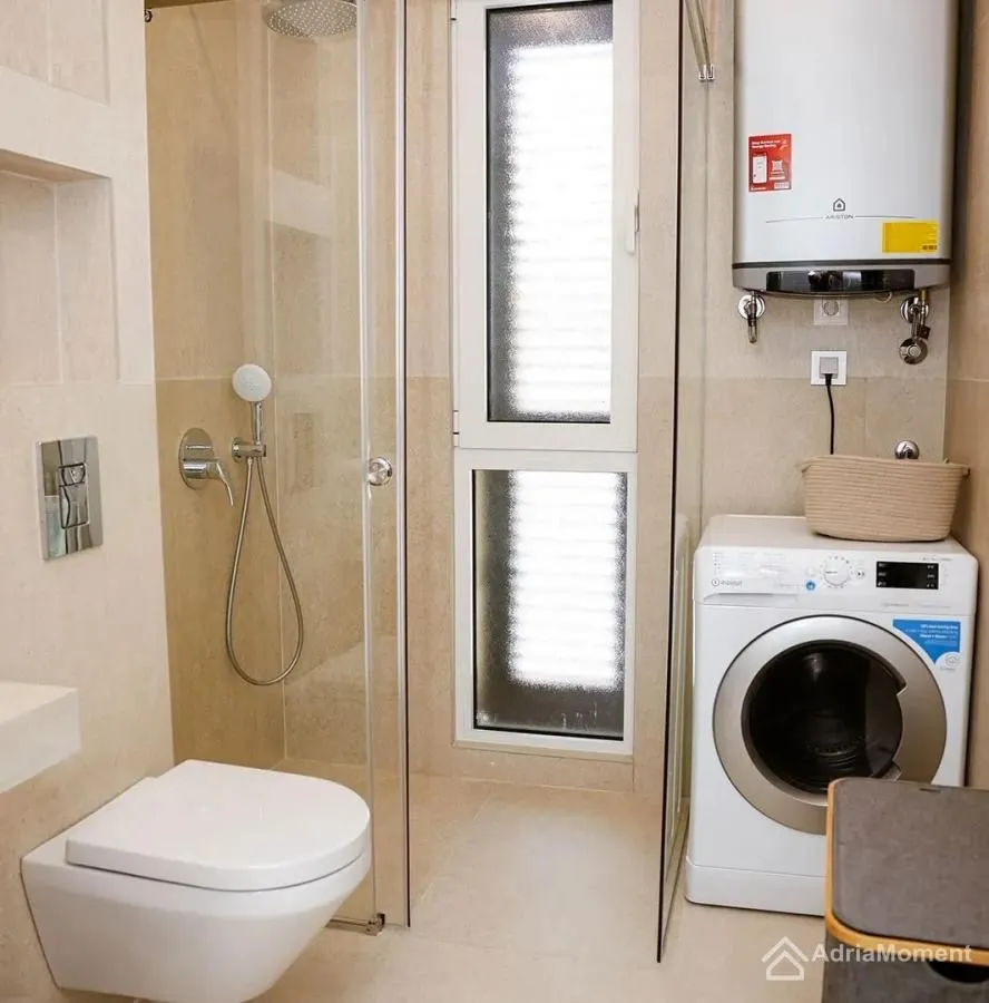 Kupatilo opremljeno tuš kabinom, WC šoljom i veš mašinom.