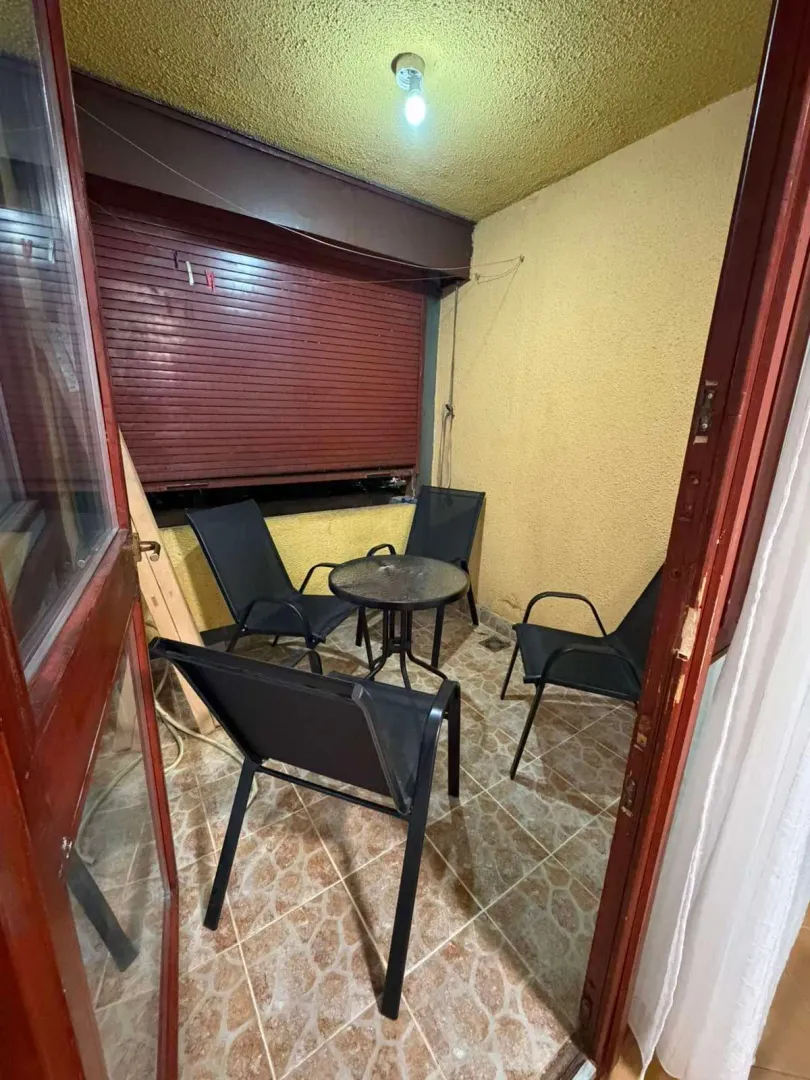 Small enclosed balcony with seating set and a small table.
