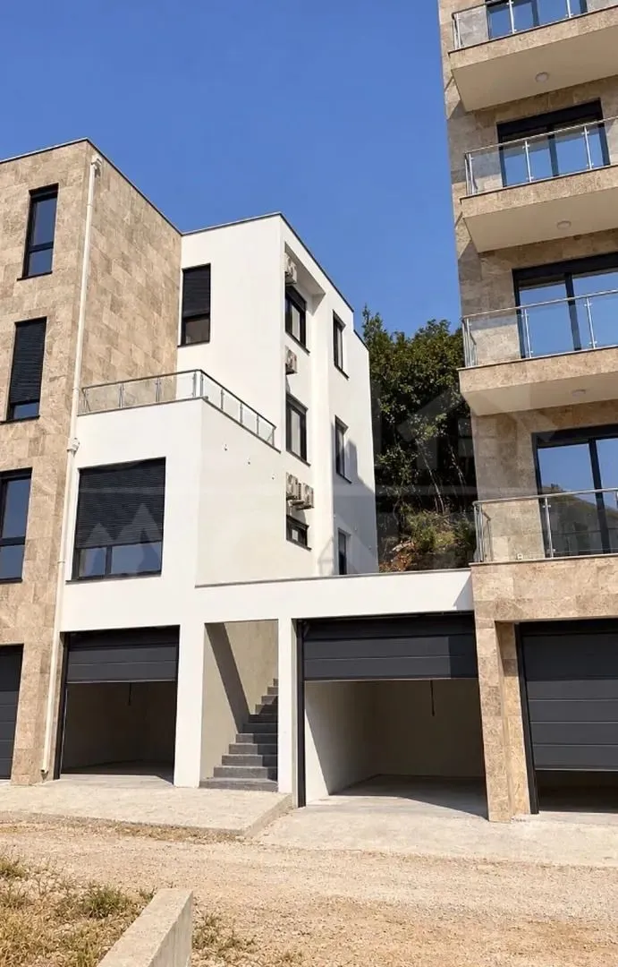 Eksterijer moderne stambene zgrade sa garažama i terasama.