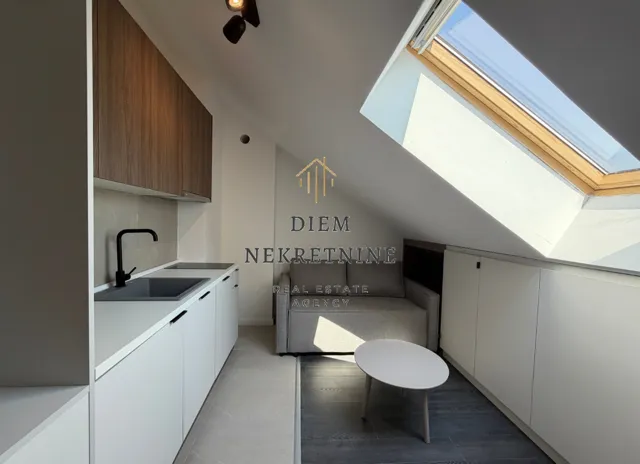 Small attic kitchen with white units and a skylight.