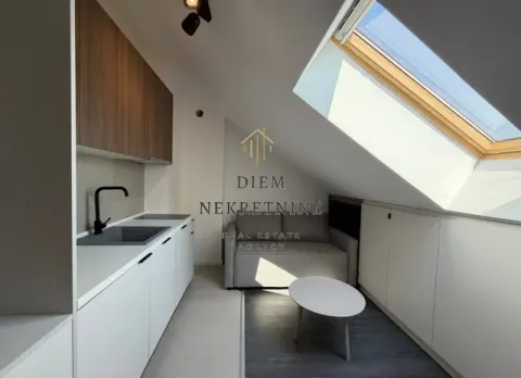 Small attic kitchen with white units and a skylight. - image 2