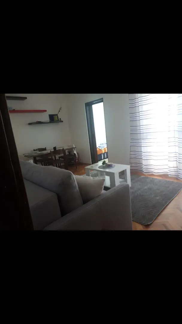 Dnevna soba sa garniturom, stočićem i trpezarijom u pozadini.
