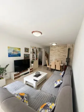 Living room with a sofa, TV, and dining area in the background. - image 2