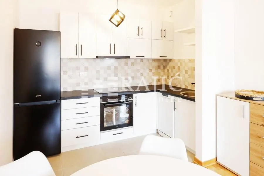 Modern kitchen with white cabinets and a black refrigerator.
