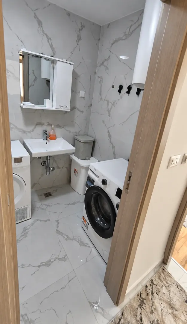 Marble-tiled bathroom featuring a washbasin and a washing machine.