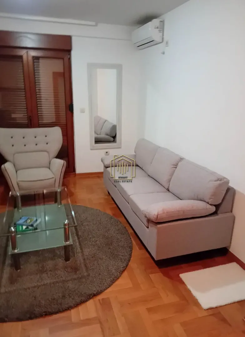 Dnevna soba sa garniturom, foteljom i staklenim stočićem.