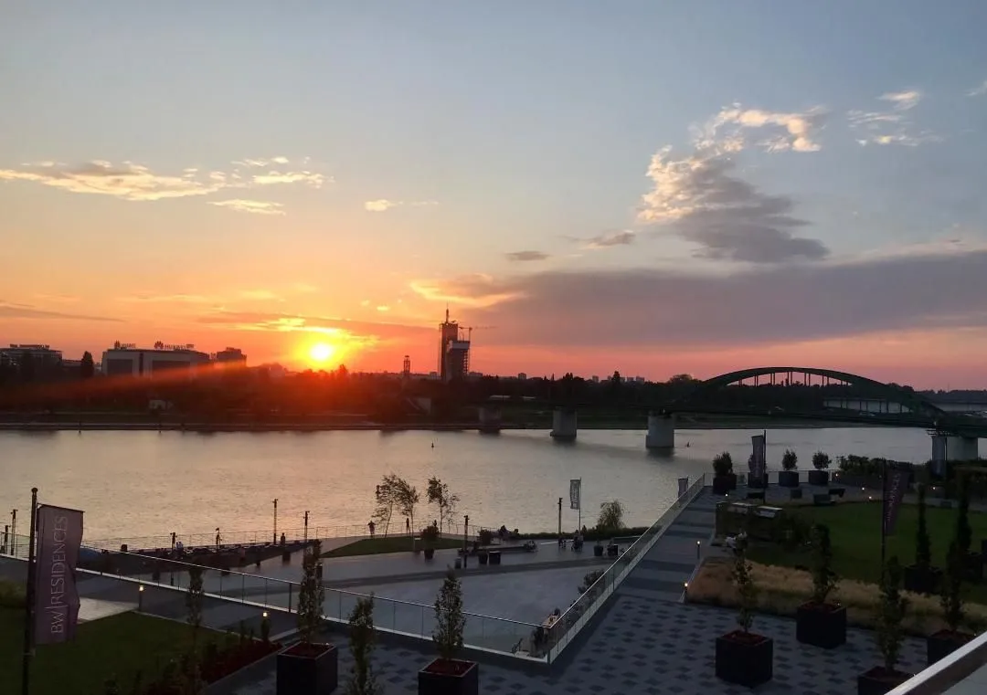 Pogled na reku i šetalište za vreme zalaska sunca.