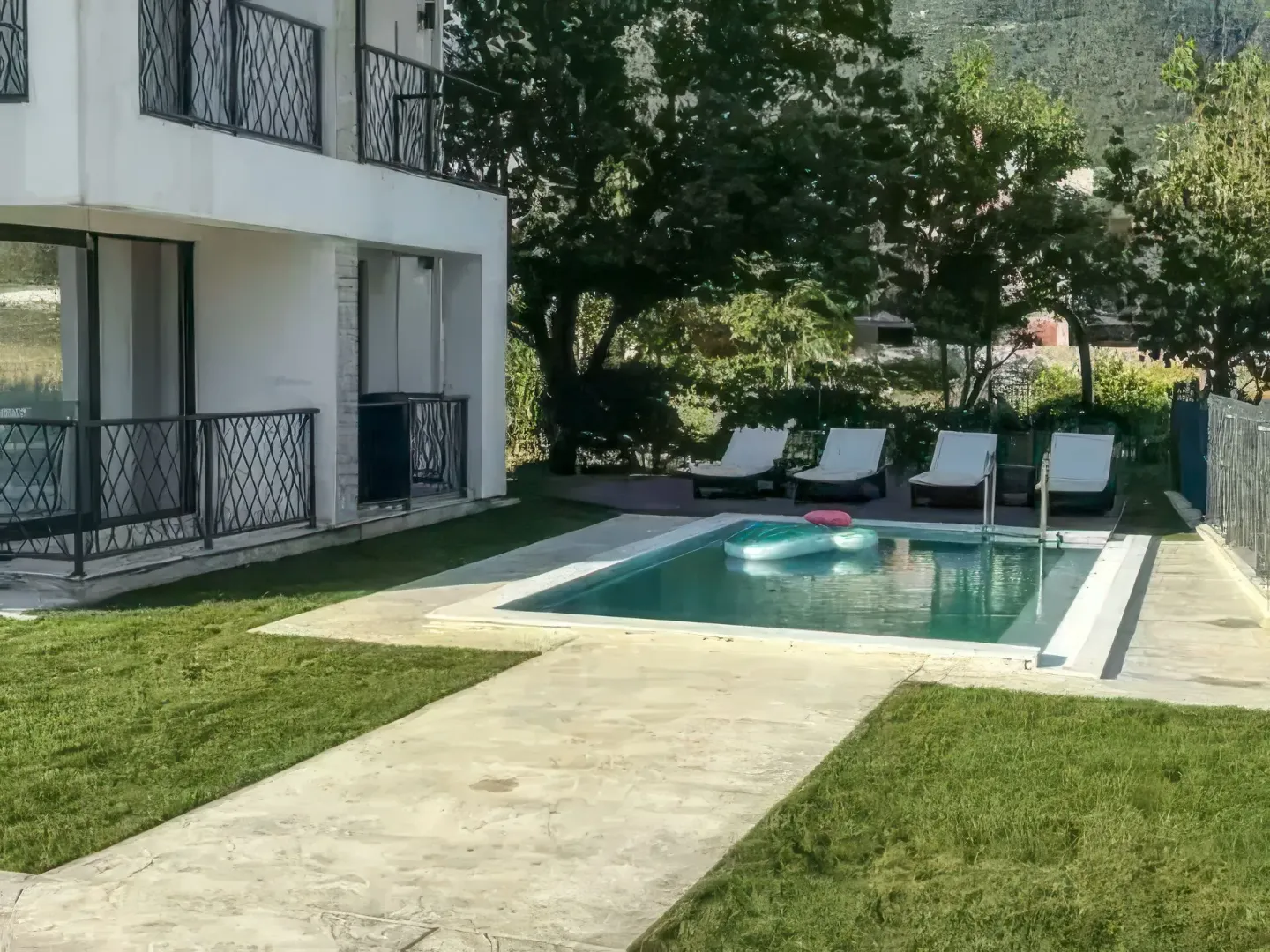 Pogled na dvorište zgrade sa bazenom i ležaljkama.