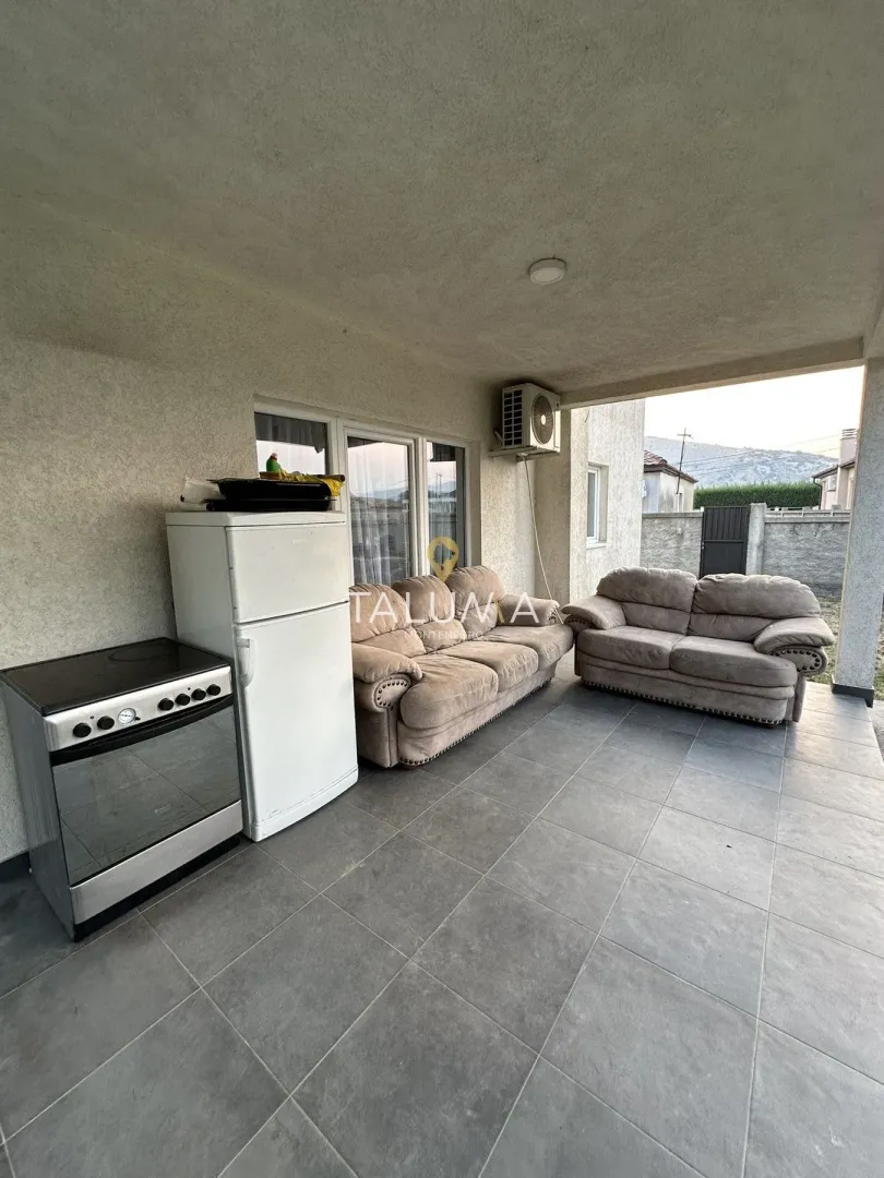 Covered terrace with seating furniture and kitchen appliances.