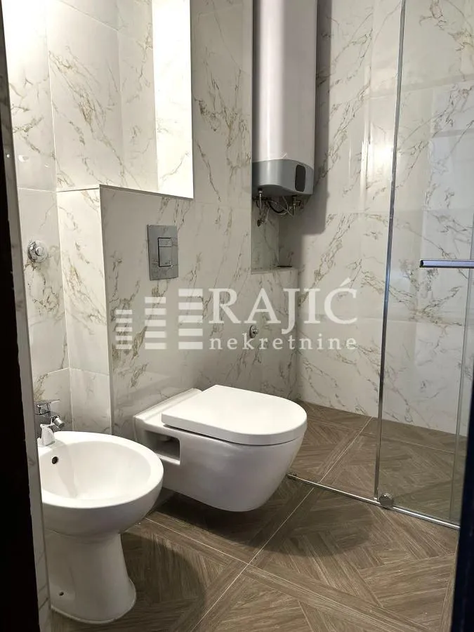Modern bathroom with white sanitary ware and marble tiles.