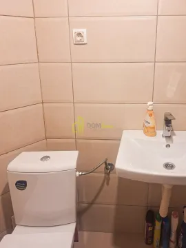 Kupatilo opremljeno umivaonikom i wc šoljom, obloženo bež pločicama. - image 5