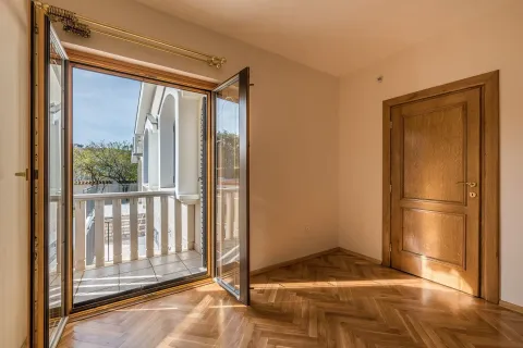 An empty room with parquet flooring and open doors leading to a balcony. - image 5