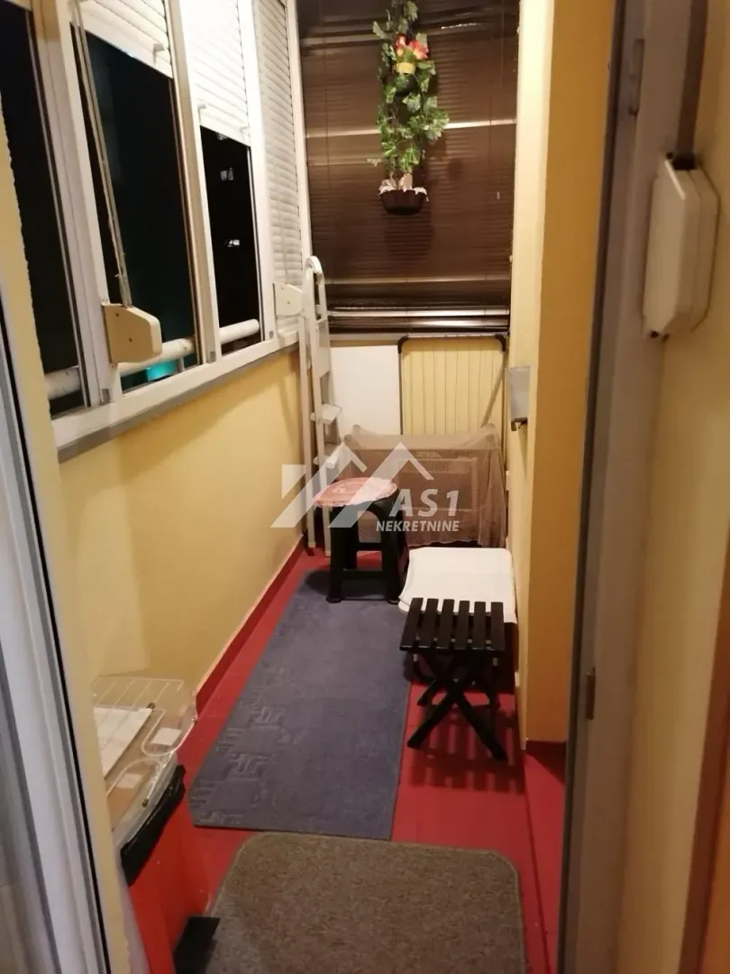 Zastakljeni balkon sa manjim stolom i stolicama.