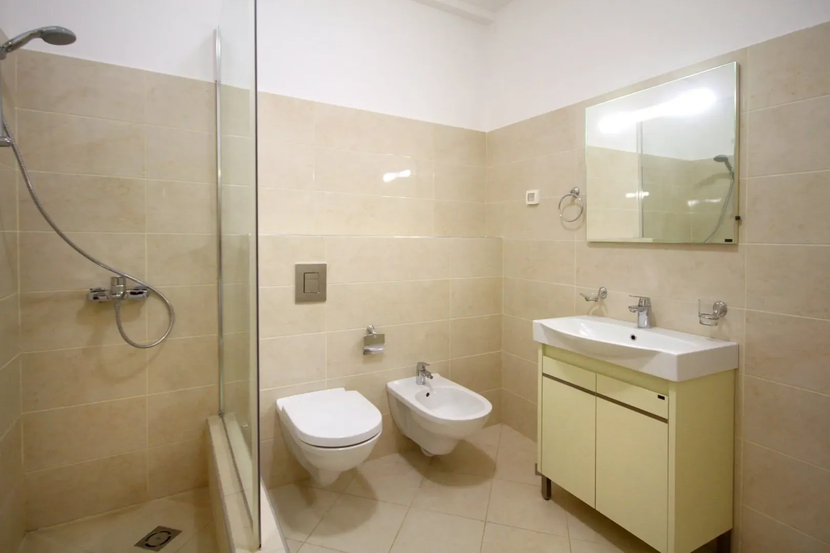 Bright bathroom with a shower cabin, sink, and bidet.