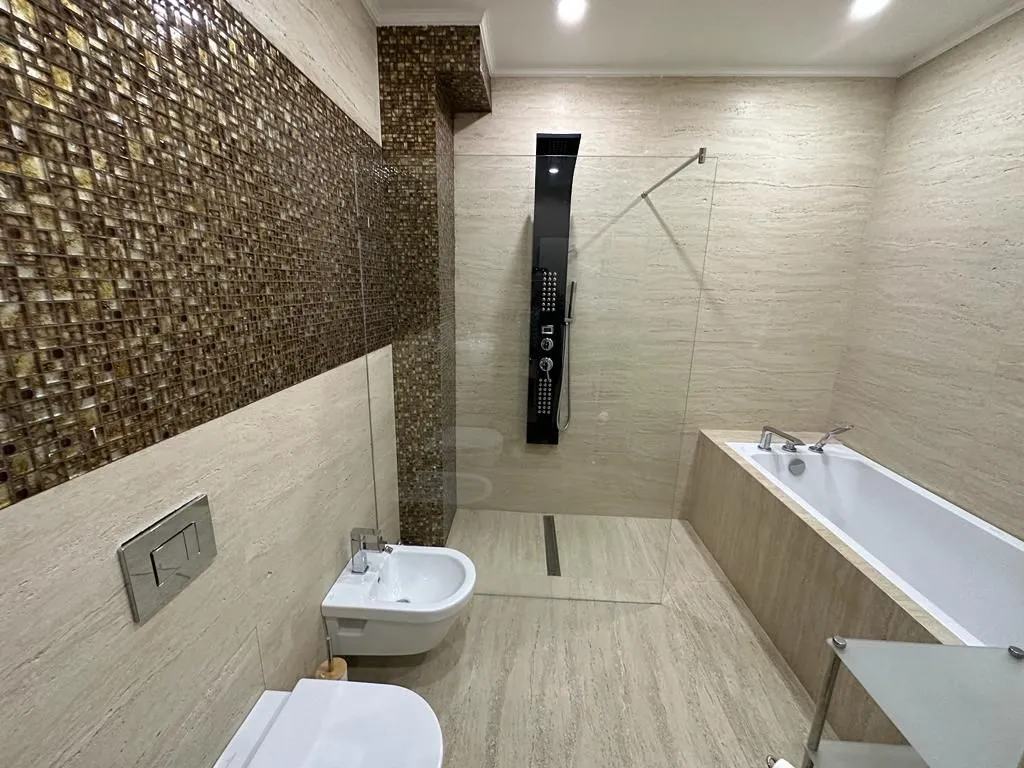 Modernly equipped bathroom with a bathtub, walk-in shower, and sanitary ware.