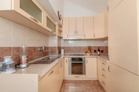 Compact kitchen with beige cabinets and built-in appliances. - image 3