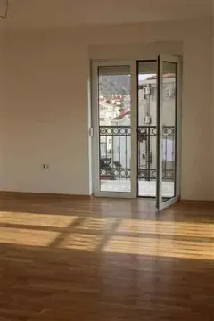 Empty room with parquet flooring and balcony doors overlooking neighboring buildings. - image 6