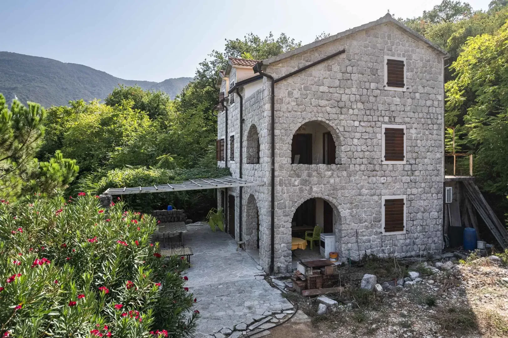 Spoljašnji izgled tradicionalne kamene kuće sa dvorištem i terasom.