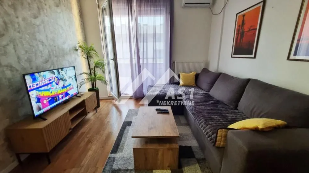 Dnevna soba sa garniturom, televizorom i izlazom na terasu.