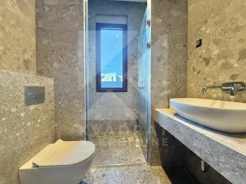 Modern bathroom clad in gray-beige tiles featuring a walk-in shower and a wall-hung toilet. - image 11
