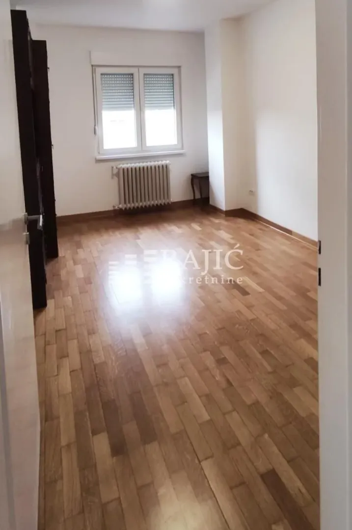 Empty room with parquet flooring and a window.