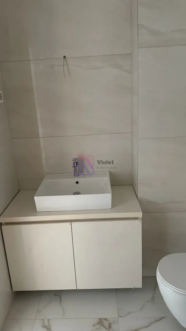 Pogled na umivaonik sa ormarićem i WC šolju u kupatilu.
