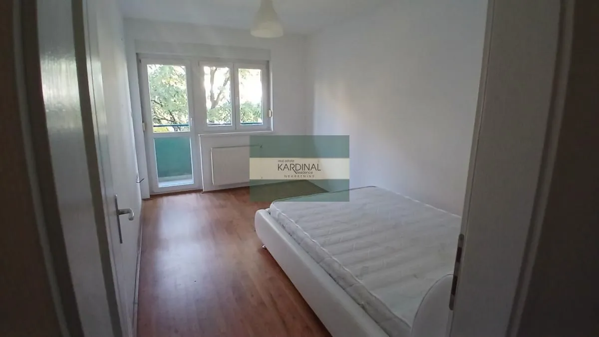 Manja spavaća soba sa krevetom i izlazom na terasu.