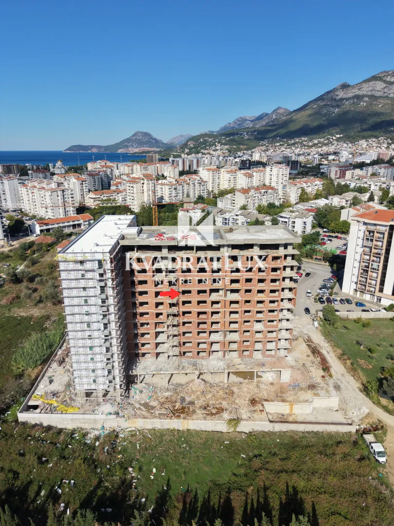 Pogled iz vazduha na stambenu zgradu u izgradnji sa okolinom i gradom u pozadini.