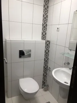 A simple bathroom with white tiles, a toilet, and a sink. - image 13