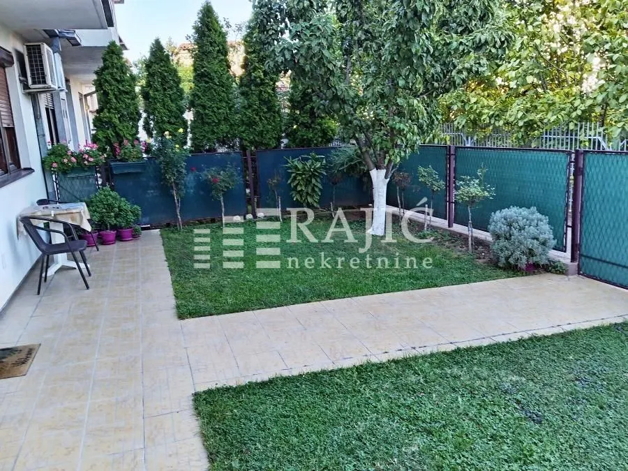 Landscaped courtyard with lawn, pathway, and greenery in front of the building.