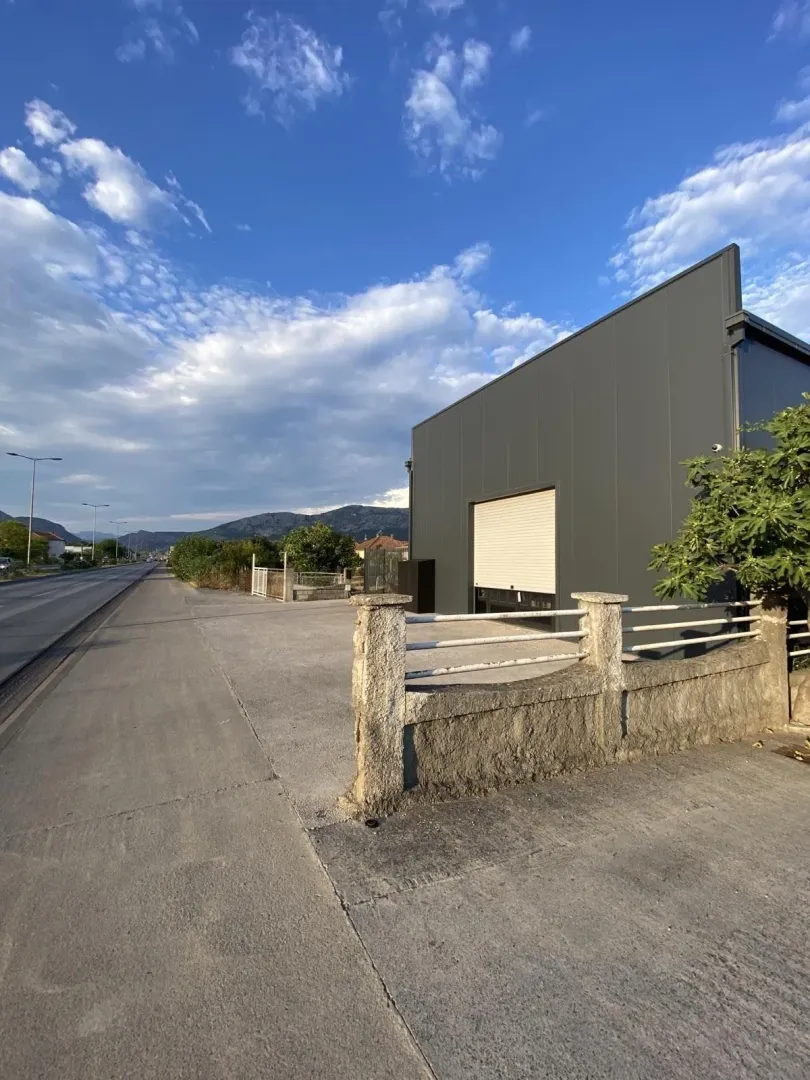 Modern grey commercial building with a roller door next to the road.