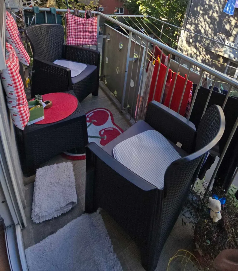 Manji namešten balkon sa garniturom za sedenje i sušenjem veša.