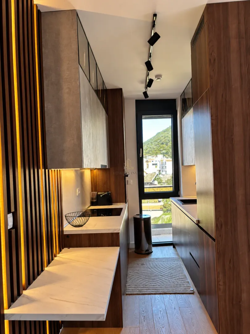 Modern narrow kitchen with wooden elements and recessed lighting.