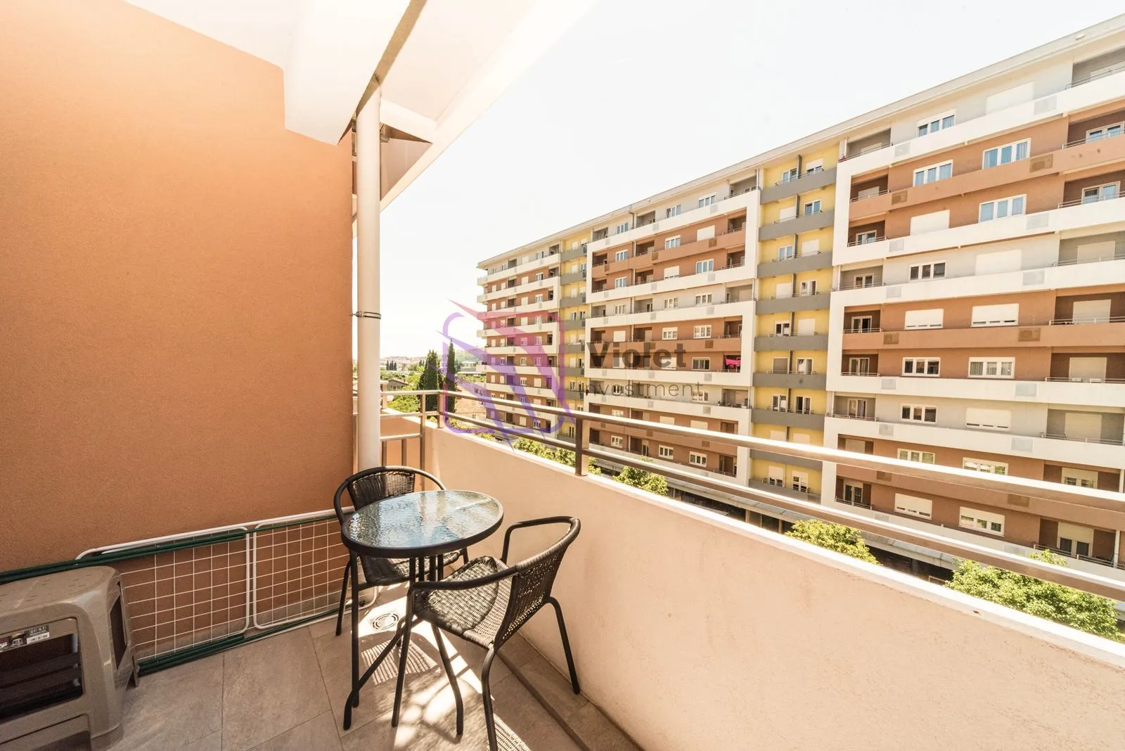 Furnished balcony with seating set and view of surrounding buildings.