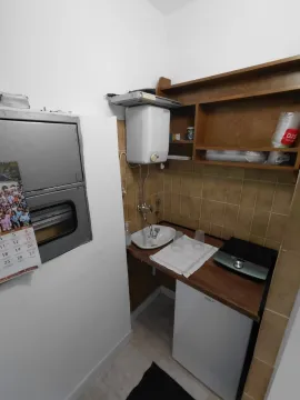 Small kitchenette with a sink, mini fridge, and shelving. - image 5