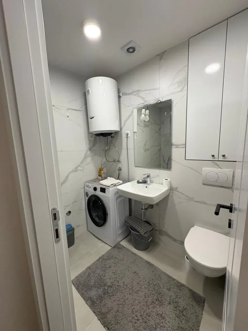 Modernly equipped bathroom with a washing machine and white ceramic tiles.