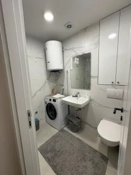 Modernly equipped bathroom with a washing machine and white ceramic tiles. - image 6
