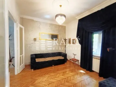 Living room with dark furniture, parquet flooring, and heavy curtains on the window. - image 4