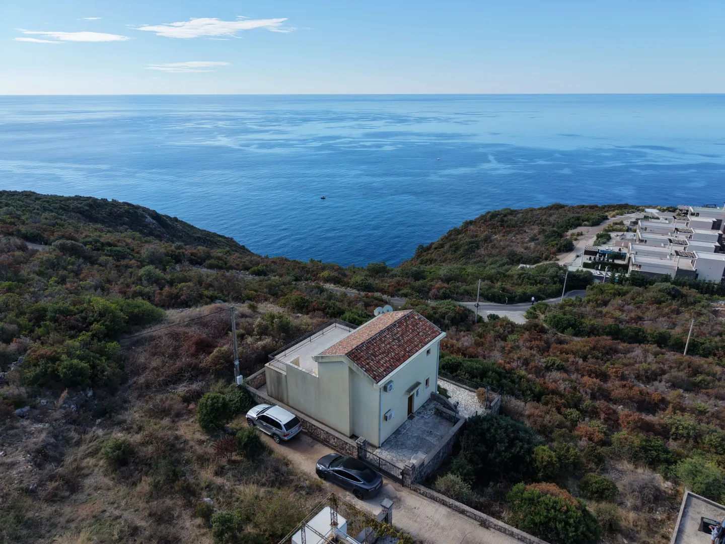 Aerial view of a house with a yard near the sea.