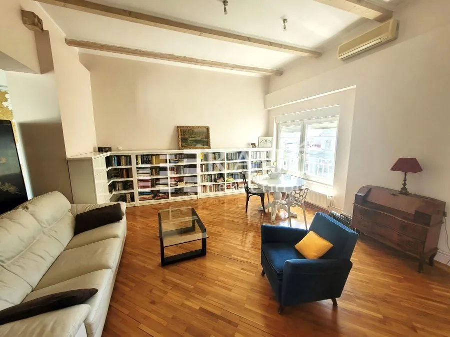 Spacious living room with a sofa, bookshelves, and a dining table.