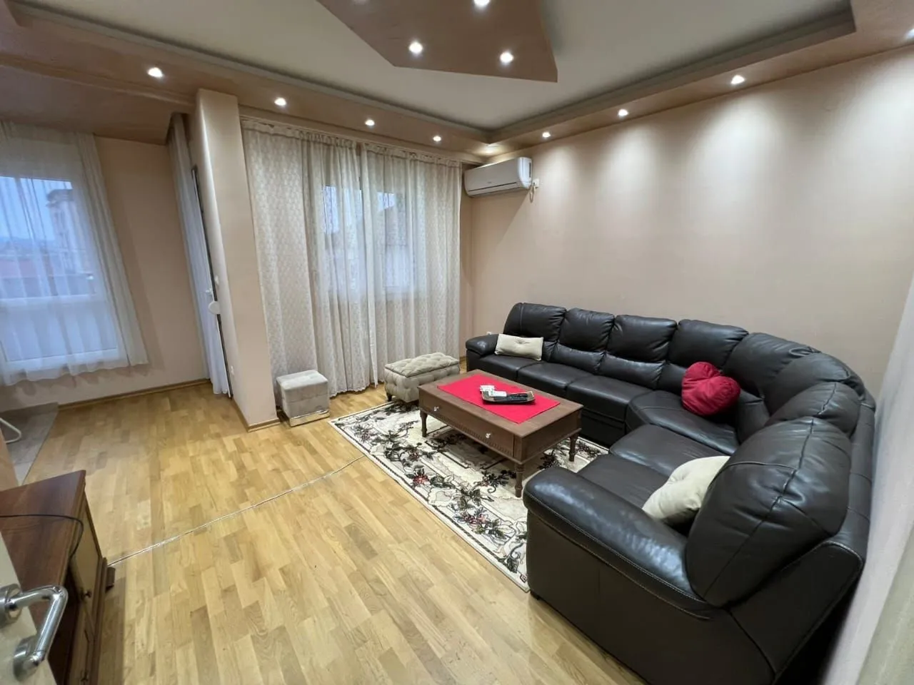 Living room with a corner sofa, coffee table, and parquet flooring.